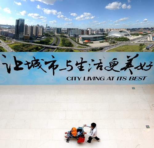 积极推进城镇化建设,城市生活更美好。上图:沈阳浑南地区景色(2013年8月30日摄)。下图:2012年9月28日,市民路过沈阳市府恒隆广场的宣传板。新华社记者 李钢 摄