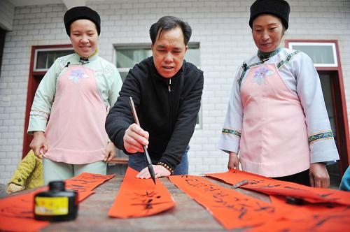 2月13日,布依族同胞写春联、迎新年。当日,在贵阳市花溪区马铃乡的水车坝布依寨里,布依族同胞们家家户户写对联、贴窗花、唱山歌,举行新年“开门”仪式,迎接虎年春节的到来。新华社记者 欧东衢 摄