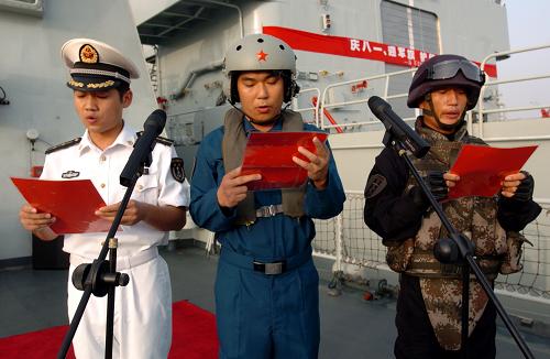 8月1日,在亚丁湾、索马里任务海区,由海军特战队员、直升机机组人员和舰艇舰员3名军人组成的护航代表,面向八一军旗宣读护航决心书。 新华社记者 郭刚 摄