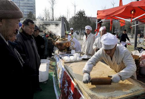 1月27日,市民在参观传统小吃麻饼的制作。春节期间,济南泉城广场举行民俗风情旅游节,各种精美的传统小吃和民俗表演吸引了众多济南市民。新华社记者 朱峥 摄