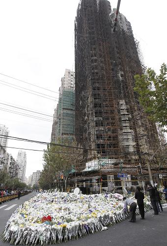 11月23日,上海“11·15”特大火灾事发大楼外堆满了菊花。 当日,上海市政府召开专题新闻发布会公布,到23日15时,上海“11·15”特别重大火灾事故58名遇难者中的57人身份得到确认。还有1名男性遇难者身份正在确认中。 新华社记者 裴鑫 摄
