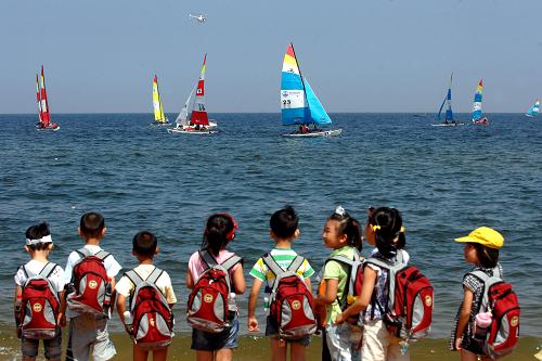 小朋友们在威海市国际海水浴场观看2012年亚太霍比级帆船锦标赛(2012年8月17日摄)。新华社记者郭绪雷摄