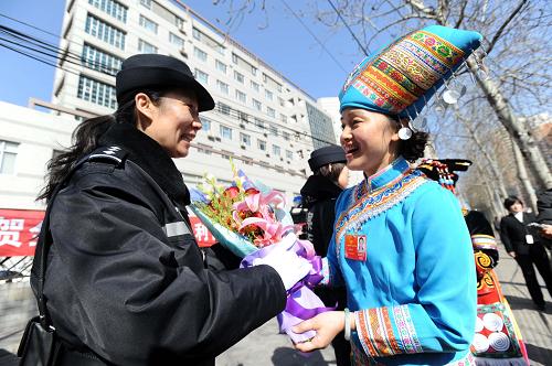 3月7日,一名来自广西壮族自治区的全国人大代表向在驻地执勤的女民警献花,向她致以节日的问候。新华社记者 陆波岸 摄