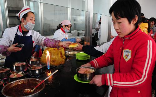 12月6日,张掖市甘州区党寨镇中心学校学生在新修建的标准化食堂打饭。 新华社记者 范培珅 摄