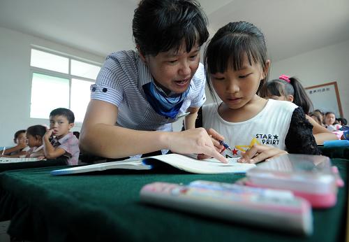 9月8日,南丰县莱溪乡中心小学六年级数学老师在为一名学生讲解课本知识。新华社记者周科摄