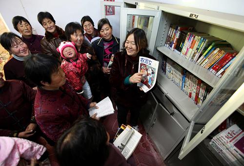 潘省莉(右一)向妇女们介绍图书刊物(2011年11月23日摄)。新华社发(闫鑫 摄)