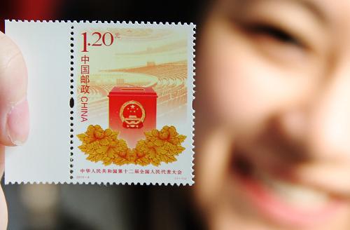 3月5日,一名集邮爱好者在江苏苏州邮政局展示刚购买的《中华人民共和国第十二届全国人民代表大会》纪念邮票。当日,中国邮政发行《中华人民共和国第十二届全国人民代表大会》纪念邮票1套1枚。邮票以投票箱为前景和主体形象,以人民大会堂内景为背景,传统的牡丹花纹样装饰于投票箱下方,面值为1.20元。新华社发(朱桂根 摄)