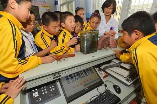 5月28日,在河北省唐山兴盛丽景小学,唐山人民医院呼吸科专家付英霞使用肺的病理标本向学生介绍烟草的危害。当日,唐山市世界无烟日宣传周正式启动,唐山市的百名控烟专家团成员将前往学校、机关、医院、社区和厂企开展形式多样的宣传活动,迎接5月31日世界无烟日的到来。新华社发(郑勇 摄)