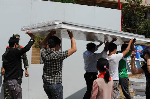 9月10日,云炉小学教师在搬运搭建临时教室的材料。当日,贵州威宁彝族回族苗族自治县石门乡云炉小学的教职工在地震灾区度过了一个特殊的教师节:他们与当地乡村干部和武警官兵一起搭建活动板房临时教室,确保学生次日能准时上学。据该校青年女教师李琳介绍,地震发生后大家最担心的是学生能不能按时开学。听说政府紧急运来了活动板房,学校的老师一大早都赶来了。“山里的孩子上学不容易。我出不了多大的力,但总可以搭上把手,做些小事”,李琳在给武警战士递工具、送矿泉水送盒饭的间隙跟记者说道。云炉小学位于贵州乌蒙大山深处。9月7日11时19分,云南彝良县与贵州威宁县交界处发生5.7级地震时,全校502名学生在老师的组织下安全撤离,无一人伤亡,3所教学楼中有1所受损。新华社记者 王念 摄