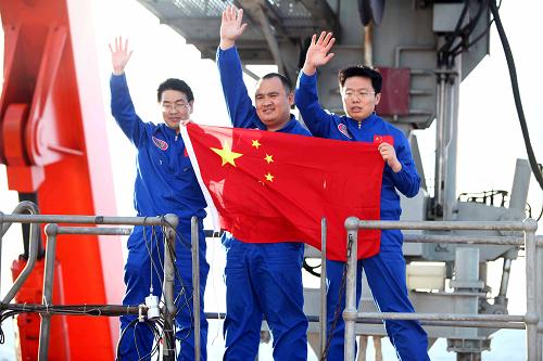 三位试航员走出“蛟龙”号载人潜水器后手举国旗挥手致意(2012年6月24日摄)。新华社记者 罗沙 摄