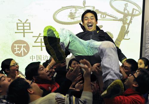 这是2012年12月23日,单车骑行中国边境募集善款凯旋而归的志愿者吴浩斌(上)接受同伴们的庆祝。今年2月起,在上海工作的志愿者吴浩斌从上海交通大学启程,历时302天环中国边境线骑行1.5万公里,进行爱心募捐。他通过“爱心里程认领”等形式募得11.8万元善款,用来帮助沿途的山区贫困学校。新华社发(汤显平 摄)