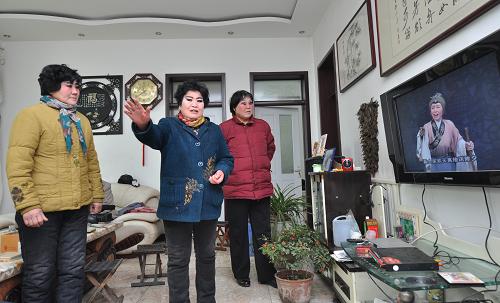 12月28日,山东省邹平县西黄村剧团的演员跟着电视光碟学习唱法。新华社发(董乃德 摄)