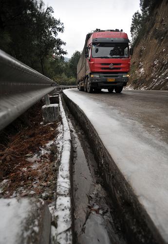 1月6日,在广西桂林市资源县资源镇通往湖南的资梅公路上,一辆货车在结冰的道路上缓慢行驶。新华社记者 陆波岸 摄