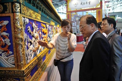 5月18日,在河北省廊坊市国际会展中心,工作人员(左一)向客商介绍滕氏布糊画。新华社发(朱旭东 摄)
