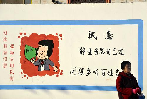宁夏中卫市沙坡头区镇罗镇河沟村一名村民从村里一文化墙前走过(1月31日摄)。新华社记者 彭昭之 摄
