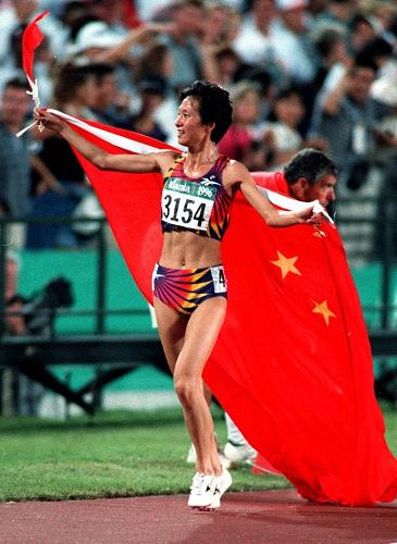 图为1996年7月28日,王军霞在获第26届亚特兰大奥运会女子5000米金牌后,身披五星红旗庆祝。新华社发
