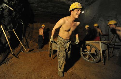 7月10日,掘进工在地下15米运土。 地下15米,闷热的空气,昏暗的光线。 来长春参与地铁一期工程快一个月了,29岁的陕西籍掘进工王飞每天都要在高温环境下负责开挖、喷锚等任务约8小时。王飞是中铁十八局集团有限公司长春地铁1号线07标段项目的一名建设者。据该标段项目经理胡恒千介绍,为了确保吉林省首条地铁于2014年5月顺利竣工,像王飞一样,近400名地铁建造工每天坚守在932.8米的工作区间内工作。 四川籍焊接工马仕双告诉记者,他们的工作环境在各类工种中温度最高,除了近距离接触焊枪外,还必须穿长袖厚衣服,戴隔热面罩和手套,一天的活干完,基本跟水洗了差不多。 长春市地铁1号线是一条贯通南北的轨道交通骨干线,线路总长18.5公里,项目于2011年8月启动,中铁十八局负责的07标段由于特殊的地质水文情况几乎成为全线施工最难的一段。每天24小时,都会有三班工人轮番上阵。 面对高温的挑战,马仕双笑着说:“我们这些农民工都是四处为家。虽然热,但是我们每天还有绿豆汤喝,有电风扇吹,还有高温补贴,挺知足的。”新华社记者 王昊飞 摄