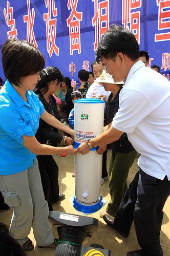 8月22日,“母亲水窖”形象大使敬一丹(左)、完美(中国)有限公司总裁胡瑞连(右)在净水设备捐赠仪式上为村民发放净水器。新华社记者 李明放 摄