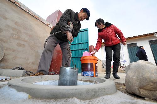 生态移民的第一个“暖冬” 12月26日,村民史腊月在家中和父亲一起从新建的水窖里打水。 时值寒冬,素有“贫瘠甲天下”之称的宁夏西海固大地刚刚经历了2012年最寒冷的日子,田地里处处覆盖着薄薄的积雪,记者来到位于西吉县震湖乡的孟湾移民新村,刚刚从大山深处搬迁到这里的100余户移民将度过他们搬迁后的第一个冬天。 孟湾村是一个以劳务输出为特点的移民村,村里家家户户的青壮年劳动力基本都外出务工,村里的村民以妇女、儿童和老年人为主。在村民史腊月宽敞明亮的新居中,卧室门边已经挂上了迎接新年的红辣椒装饰,史腊月和几位邻居正在炉子边烤火聊天,进入冬季之后,搬迁来的移民家家户户都领到了冬季取暖用的新炉子和1吨煤。史腊月的儿子正在村里的移民点小学上课,虽然离家很近,但是因为中午学校有免费午餐,所以她儿子每天中午都留在学校吃午饭,“他总说学校的饭更香!”史腊月笑着说。 眼下正是农闲时节,在村里,记者走访了好几户,都没有看到村民们聚在一起打牌喝酒,反而在村部的农家书屋内,记者见到了几位正在翻阅牛羊饲养方式书籍的村民,一位村民告诉记者,到明年,他家就要开始收拾牛棚养肉牛