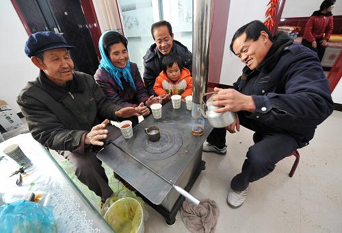 生态移民的第一个“暖冬” 12月26日,在村民史腊月家中,几位邻居和史腊月的父母(左一、左二)一起围炉烤火聊天。 时值寒冬,素有“贫瘠甲天下”之称的宁夏西海固大地刚刚经历了2012年最寒冷的日子,田地里处处覆盖着薄薄的积雪,记者来到位于西吉县震湖乡的孟湾移民新村,刚刚从大山深处搬迁到这里的100余户移民将度过他们搬迁后的第一个冬天。 孟湾村是一个以劳务输出为特点的移民村,村里家家户户的青壮年劳动力基本都外出务工,村里的村民以妇女、儿童和老年人为主。在村民史腊月宽敞明亮的新居中,卧室门边已经挂上了迎接新年的红辣椒装饰,史腊月和几位邻居正在炉子边烤火聊天,进入冬季之后,搬迁来的移民家家户户都领到了冬季取暖用的新炉子和1吨煤。史腊月的儿子正在村里的移民点小学上课,虽然离家很近,但是因为中午学校有免费午餐,所以她儿子每天中午都留在学校吃午饭,“他总说学校的饭更香!”史腊月笑着说。 眼下正是农闲时节,在村里,记者走访了好几户,都没有看到村民们聚在一起打牌喝酒,反而在村部的农家书屋内,记者见到了几位正在翻阅牛羊饲养方式书籍的村民,一位村民告诉记者,到明年,他