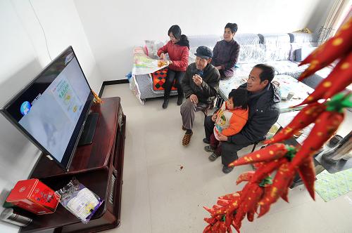 生态移民的第一个“暖冬” 12月26日,村民史腊月(左一)在家里和父母、邻居一起看电视。 时值寒冬,素有“贫瘠甲天下”之称的宁夏西海固大地刚刚经历了2012年最寒冷的日子,田地里处处覆盖着薄薄的积雪,记者来到位于西吉县震湖乡的孟湾移民新村,刚刚从大山深处搬迁到这里的100余户移民将度过他们搬迁后的第一个冬天。 孟湾村是一个以劳务输出为特点的移民村,村里家家户户的青壮年劳动力基本都外出务工,村里的村民以妇女、儿童和老年人为主。在村民史腊月宽敞明亮的新居中,卧室门边已经挂上了迎接新年的红辣椒装饰,史腊月和几位邻居正在炉子边烤火聊天,进入冬季之后,搬迁来的移民家家户户都领到了冬季取暖用的新炉子和1吨煤。史腊月的儿子正在村里的移民点小学上课,虽然离家很近,但是因为中午学校有免费午餐,所以她儿子每天中午都留在学校吃午饭,“他总说学校的饭更香!”史腊月笑着说。 眼下正是农闲时节,在村里,记者走访了好几户,都没有看到村民们聚在一起打牌喝酒,反而在村部的农家书屋内,记者见到了几位正在翻阅牛羊饲养方式书籍的村民,一位村民告诉记者,到明年,他家就要开始收拾牛棚养肉牛