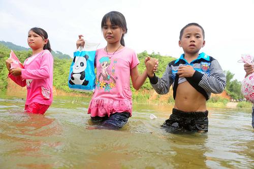 涉水求学路 9月9日,在广西藤县古龙镇陈平村小学通往那龙组的桥上,放学回家的孩子们涉水通过桥面。 广西藤县古龙镇陈平村那龙组在陈平村小学就读的10多名五、六年级学生仍需涉水求学。9月9日,记者在那龙组通往陈平小学的桥上看到,大桥已经被水淹没,来往的村民只能涉水通行。下午4时许,那龙组10多名放学的孩子,走到桥头,没有脱衣服就走上被水淹没的桥面,手牵着手,举着书包在齐腰深的水里艰难前行。孩子们告诉记者,每年雨季水库涨水,上学必经之路的大桥就被水淹没,一年最长有2、3个月,他们每天都要在水里往返,穿着湿衣服去学校上课,靠体温把衣服慢慢暖干。 对于需要到陈平村小学就读的五、六年级学生,出于安全起见,学校要求他们暂时停课在家,但孩子们担心学习受到影响,仍坚持涉水上课。 据村民介绍,每逢雨季水库涨水,村民、学生都需要涉水通行,这种状况从上世纪70年代开始,已经持续30多年。 新华社记者 黄孝邦 摄