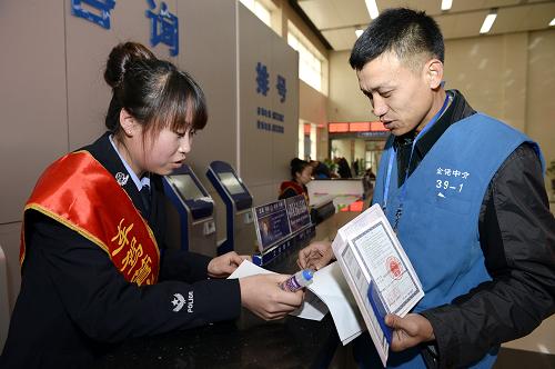 一位中介工作人员身穿蓝色马甲在银川车管所大厅代办业务(11月13日摄)。宁夏银川市车辆管理所自2013年开始,针对周边部分“黑中介”代办机动车业务乱要价、诈骗等现象,展开对中介市场的净化管理行动。针对辖区内199家合法中介进行摸底调查,建立档案,按要求将代办项目、收费标准、代办人员工作照进行公示。代办员进入办事大厅代办业务统一身着蓝色小马甲,佩戴工作牌。该管理方式运行以来,有效规范了机动车代办业务市场,方便了办事群众。新华社记者 王鹏 摄