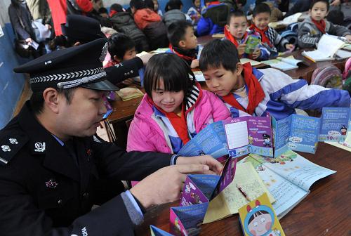 2月13日,法制辅导员在给广西南宁市外来务工人员子弟学校——金太阳小学的孩子们讲解《小学生安全手风琴》漫画宣传册。新华社记者 周华 摄