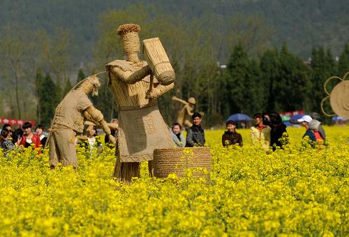 仙居县双庙乡的大片油菜花盛开,一组反映当地群众从事传统农业生产的稻草人竖立在其中(3月27日摄)。新华社记者 徐昱 摄