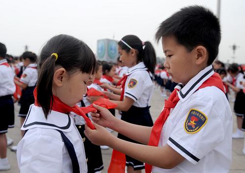 6月1日,刚加入少先队、来自北京海淀区枫丹实验小学一年级的吴笑嫣(左)在老队员的帮助下佩戴红领巾。新华社记者 罗晓光 摄
