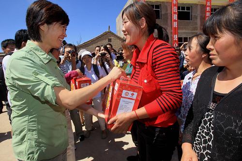 8月23日,“母亲水窖”形象大使敬一丹(左一)在甘肃省定西市临洮县上营乡举行的“母亲邮包”发放仪式上向当地妇女发放“母亲邮包”。新华社记者 李明放 摄