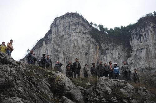 2月19日早晨,事发山体发生新一轮崩塌,当地村民在事发现场查看崩塌情况。截至2月19日13时,贵州凯里龙场镇山体崩塌仍在持续,被困5人仍下落不明,大量石块阻断山下河流形成堰塞湖,国土资源部相关专家已赶到现场指导抢险,专家组初步分析认为,此次崩塌石方已超过20万立方米,崩塌最高点距离地面250米,属大型山体垮塌灾害。2月18日11时30分许,贵州省黔东南州凯里市龙场镇一山体发生崩塌,导致5人被埋。新华社发(陶亮 摄)