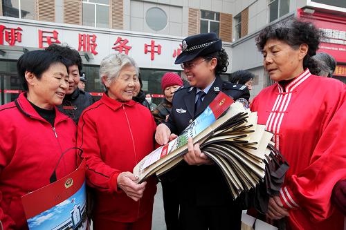 11月14日,枣庄市公安局市中分局文化路派出所民警在立新小区向参加晨练的居民发送预防诈骗宣传手册、新春年画和环保购物袋等宣传物品。新华社发(吉喆 摄)