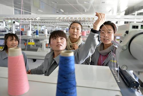 宁夏灵武市泾灵新村农民在移民村里的一家羊绒制品加工企业学习纺织技术(12月11日摄)。 新华社记者 王鹏 摄