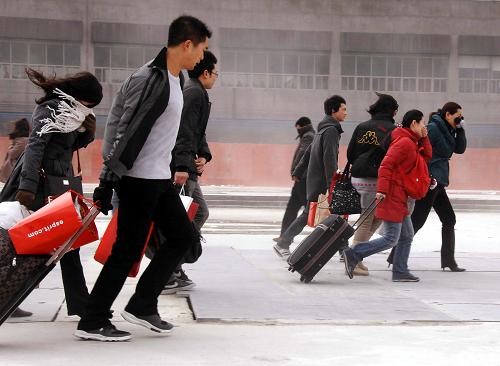 2009年1月23日,上海市铁路迎来节前客流高峰,乘客顶着大风从铁路上海站进站。新华社发