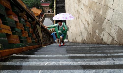 7月9日,游客在雨中踏着贴有防滑条的石阶游览颐和园佛香阁。新华社记者 李欣 摄