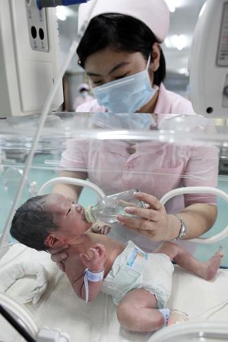 2月11日,在江苏省赣榆县人民医院新生儿重症监护室,一名护士在给患儿喂水。新华社发(司伟 摄)