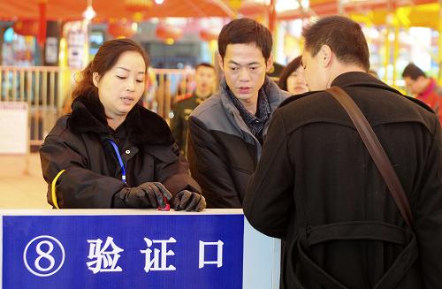2月15日,在江西九江火车站进口处,南昌铁路局九江桥工段的工作人员在为旅客检票。新华社发(胡国林 摄)