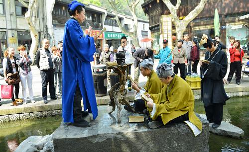 4月12日,游客和市民在观看演员表演陆羽讲《茶经》的情景剧。新华社发(龙巍 摄)