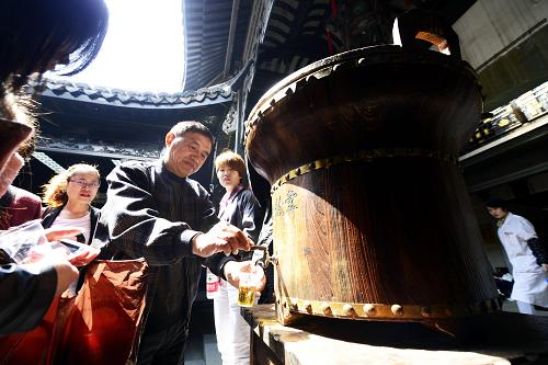 4月12日,游客在杭州河坊街上一家老字号药房里品尝免费药茶。新华社发(龙巍 摄)
