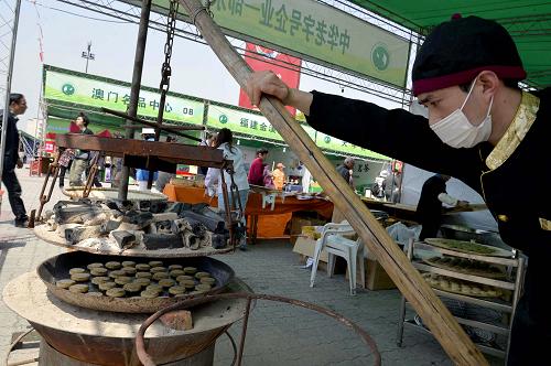 4月12日,一家参展企业在“清河坊民间茶会”上烘烤传统名点茶饼。新华社发(龙巍 摄)