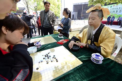 4月12日,游客在杭州吴山景区与古装棋手一起品茗对弈。当日,一年一度的“清河坊民间茶会”在杭州清河坊历史街区和吴山景区开汤启幕。为期七天的民间茶会以“斗茶—问茶—赏茶—品茶—展茶—忆茶”为主线,推出大碗茶比赛、老街问茶、请到我家来喝茶、茶叶茶具展销会、微博话茶、老茶新说等系列活动,全面展现“茶都”杭州悠久的民俗茶文化。新华社发(龙巍 摄)