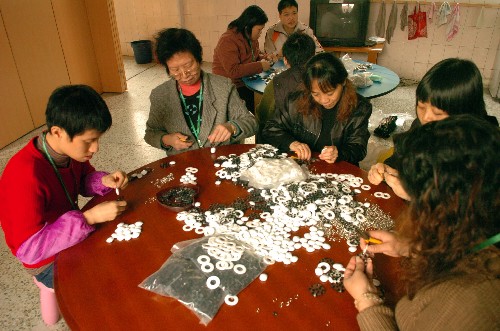 2007年12月3日,几位智障人士和家长一起在广州德福之家加工手工艺品。广州德福之家专门为那些从特殊学校结业后没有找到工作的人士提供工作及生活技能培训。目前这里聚集着十多位残疾人,从事一些热心机构和个人提供的适合他们的工作,从中体验工作的成就感。 新华社记者 壮锦 摄