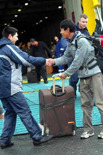 2月26日,在希腊克里特岛,希腊服务人员和从利比亚撤离至此的中方人员握手。2898名中方人员乘坐中国驻希腊大使馆租用的“韦尼泽洛斯”号客轮于当地时间26日上午抵达克里特岛。 新华社发(马里奥斯·罗洛斯 摄)