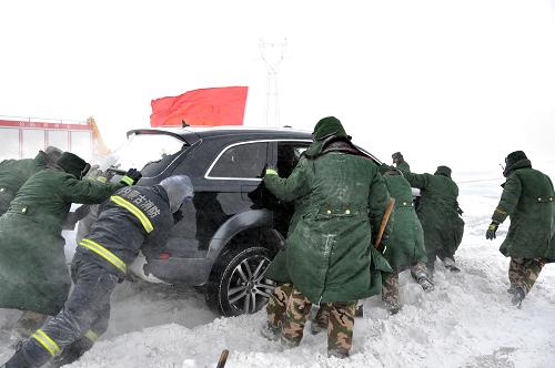 1月22日,消防战士正在将一辆被困车辆从雪窝里推出。因受大风降雪袭扰,从当日清晨开始,内蒙古自治区呼(和浩特)海(拉尔)省际大通道S105化德县与正镶白旗之间的部分路段陆续被大雪掩埋,并造成上百辆汽车被困,幸无人员伤亡。新华社发(田瑜 摄)