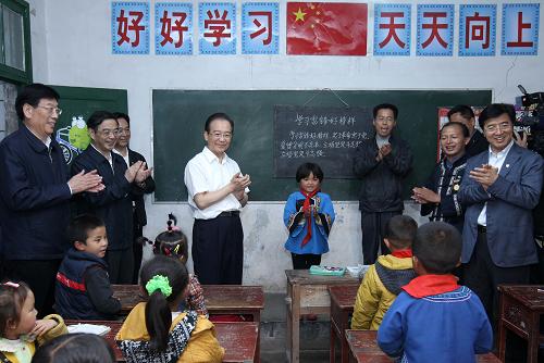 5月25日,在古丈县默戎镇毛坪村教学点——毛坪小学,温家宝疼爱地看着孩子们说:“大家唱个歌吧!”孩子们高兴地喊道:“好!”。一个5岁的苗族小姑娘跑上讲台主动要当指挥。孩子们稚嫩的歌声打动着现场的人们。新华社记者 庞兴雷 摄