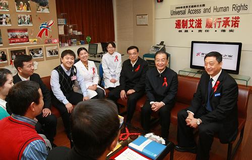 12月1日,中共中央政治局常委、国务院总理温家宝和中共中央政治局常委、国务院副总理李克强来到位于北京地坛医院的北京红丝带之家,看望这里的艾滋病感染者、医护人员和志愿者,并主持召开座谈会,听取专家对艾滋病防治工作的意见和建议。这是温家宝、李克强在位于地坛医院的北京红丝带之家与艾滋病患者(两位、背影)、志愿者及医护人员交谈。 新华社记者 庞兴雷 摄