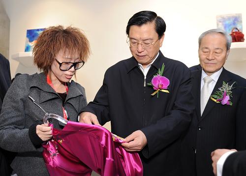 3月29日,中共中央政治局委员、国务院副总理张德江参观第19届中国国际服装服饰博览会。这是张德江在展台内向工作人员了解服装面料的使用情况。 新华社记者王晔摄