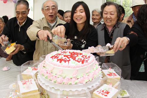 10月22日,一名大学生志愿者和社区老人一起切寿糕。当日,天津市开展“九九重阳节,浓浓敬老情”系列活动,来自高校和社区的志愿者为老人院和社区散居老人送寿糕、义务体检,与老人们一起共迎重阳佳节到来。新华社发(李想 摄)