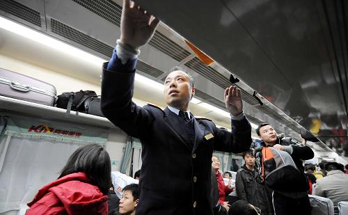 1月8日,长沙开往上海的旅客列车上出现“学生潮”,一名乘务员在其中整理行李架。 新华社记者 赵众志 摄